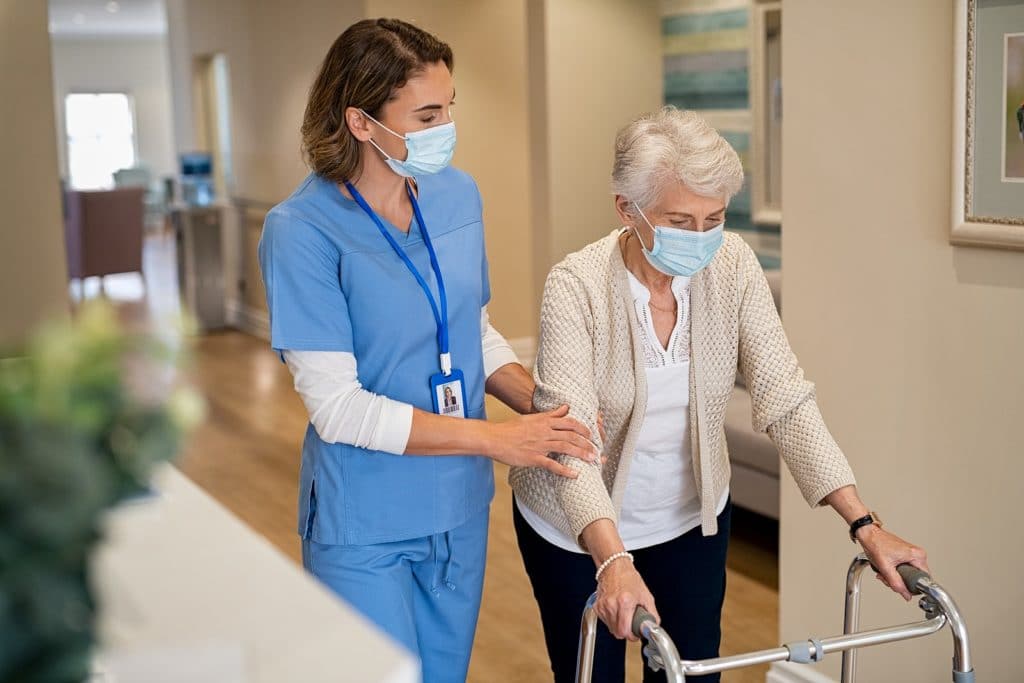 Senior and nurse taking covid precautions in senior living