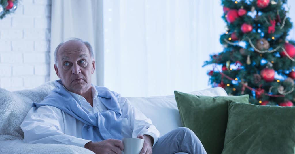 older man sitting on couch, alone during the holidays