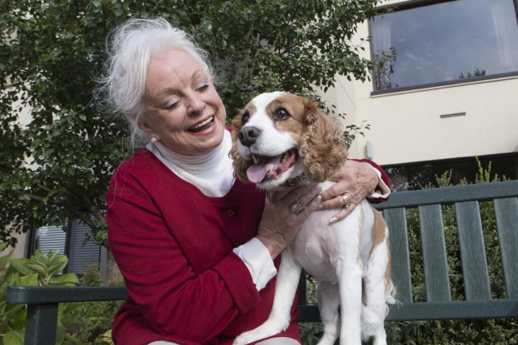 senior woman smiling and sitting with a smiling dog