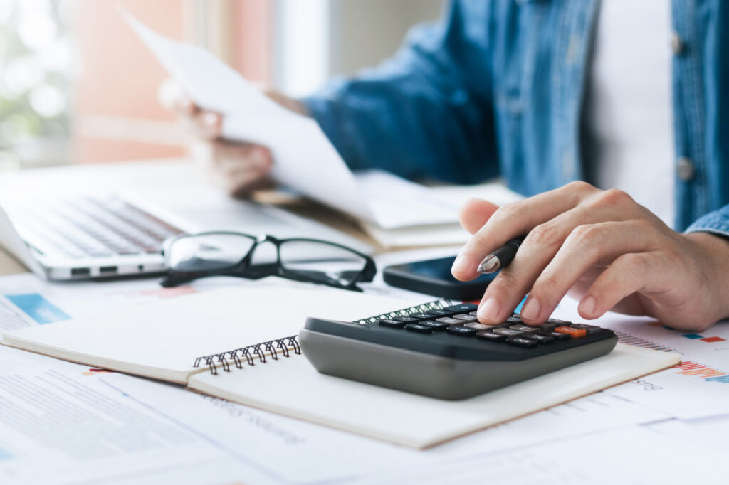 close up of a hand holding papers & using a calculator