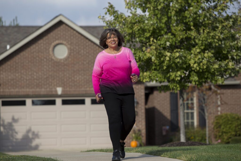 A resident of Westminster Village walking down the sidewalk in front of a senior residential home
